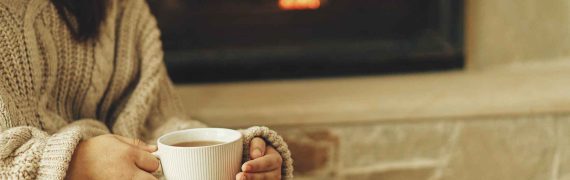Girl with cup by the fireplace